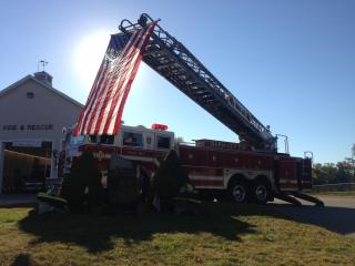 Fire truck from whose ladder hangs the American flag