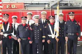Uniformed Men standing regally before a firetruck